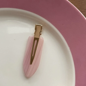 Detail shot of the pink marble resin hair clip with golden metal duckbill clamp
