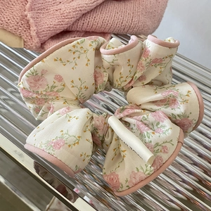 Macro d'un chouchou à fleurs beige et rose avec des motifs de roses et bordure rose