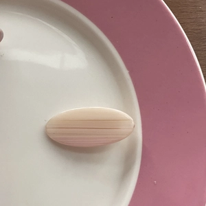 Pink and cream marble texture acrylic hair clip on an elegant porcelain plate