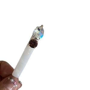 Barrette élégante en acétate blanc avec strass brillants tenue par une main sur fond blanc