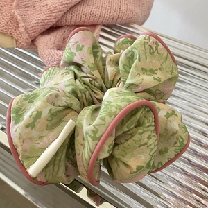 Chouchou fleuri vert et rose avec bordure contrastée sur plateau en verre