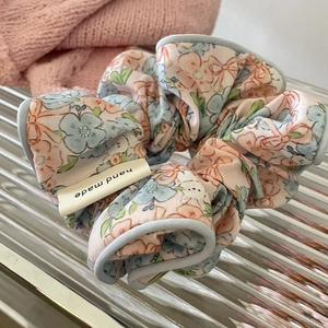 Chouchou floral fait main en rose et bleu sur un plateau en verre transparent