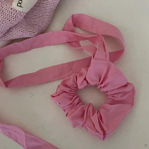 Detailed close-up of a pink ribbon scrunchie with long streamers on a cream background
