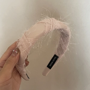 Detail of light pink feathered headband with handmade label and woven fabric texture