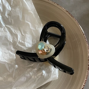 Elegante molletta nera a cuore con strass colorati su un piatto di ceramica