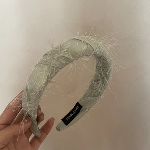 Light green feather headband with thick satin base and handmade craftsmanship label
