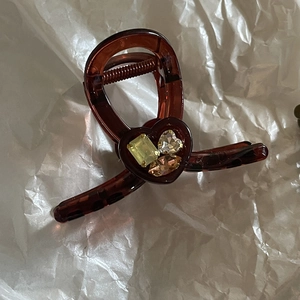 Dettaglio macro di una pinza per capelli in resina tartarugata con strass a cuore colorati