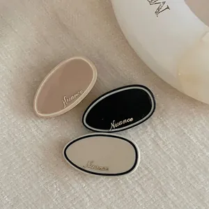 Three-piece set of premium acetate oval hair clips in black, brown and beige with gold logo