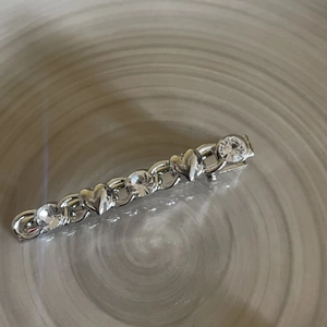 Detailed macro view of silver heart hair clip with sparkling rhinestones and chain link