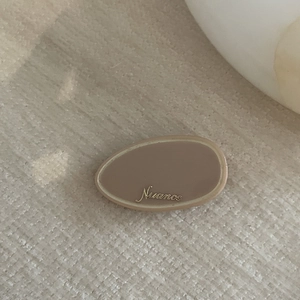 Detail of premium beige acetate hair clip with golden Nuance lettering on wood background
