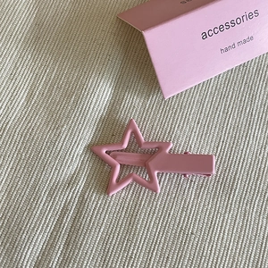 Fermaglio a stella in metallo rosa opaco con design traforato su tessuto strutturato