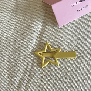 Primo piano di un fermaglio per capelli a stella in metallo giallo su carta rosa