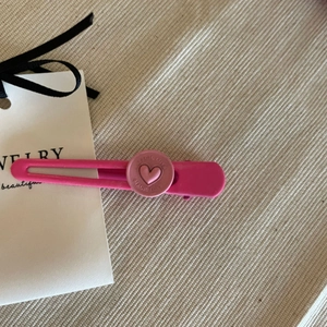 Detailaufnahme der rosa Herz-Haarklammer mit Magic Love Gravur auf weißer Karte