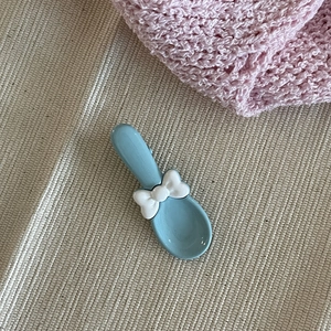 Vue détaillée d'une pince à cheveux cuillère bleu clair avec nœud blanc mignon