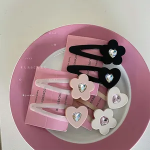 Detail von Herz- und Blumenhaarklammern mit Strasssteinen in Pink, Schwarz und Weiß