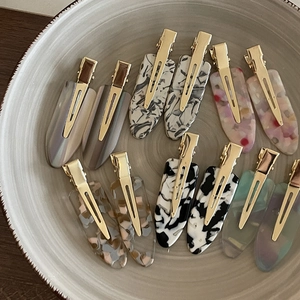 Set of minimalist acetate hair clips with diverse patterns on a ceramic plate