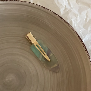 Elegant gold metal hair clip with translucent floral acetate on a ceramic tray display