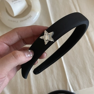 Detail of black sponge headband featuring a silver star ornament with an inlaid gemstone