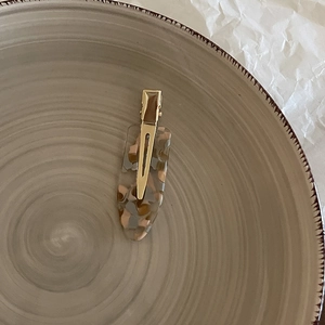 Elegant Korean acetate hair clip with marble pattern and gold metal clip on ceramic plate