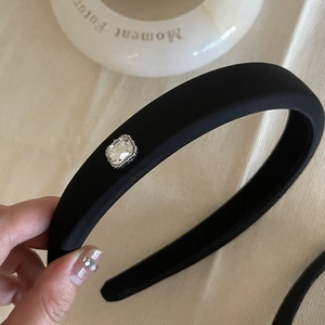 Detail of black padded headband featuring a large emerald-cut crystal in silver setting
