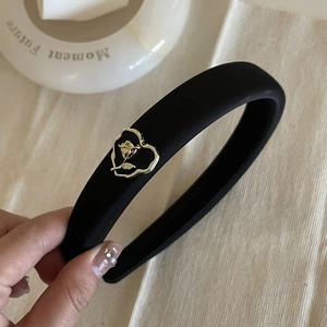 Close-up of black matte sponge headband with gold rose embossment and heart frame