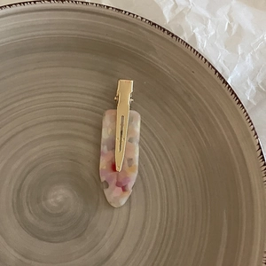 Detail of colorful acetate hair clip with pink and purple textures on a ceramic tray
