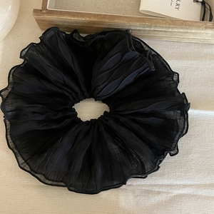Dettaglio dell'elastico per capelli in chiffon nero con elegante trama a pieghe