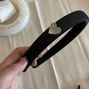Detail of black sponge headband featuring a small silver heart with a rhinestone