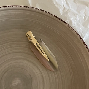 Close-up of a premium tortoiseshell resin hair clip on a minimalist ceramic plate