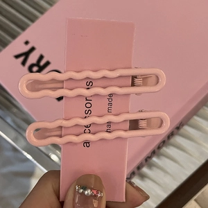 Zweiteiliges Set aus rosa wellenförmigen Metall-Haarklammern auf einer dekorativen Karte