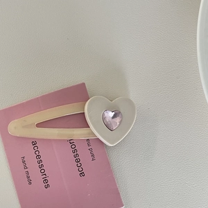 Glänzende Haarspange mit rosa Herz und cremefarbener Basis auf einer Accessoire-Karte