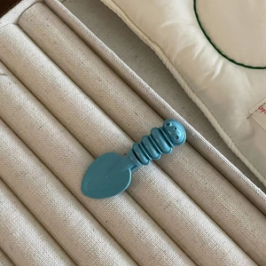 Detailed macro view of a cute blue candy-colored caterpillar hair clip with a smiley face