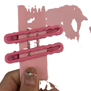 Set mit zwei rosa wellenförmigen Metall-Haarspangen auf dekorativer Kartenverpackung