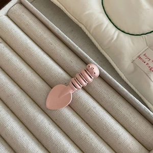 Close-up of pink candy-colored spoon hair clip with glossy finish on display tray