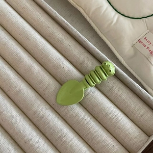 Close-up of a green candy-colored spoon hair clip with a cute caterpillar-shaped handle