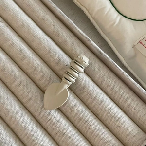 Macro shot of cream-colored spoon hairpin with high-gloss enamel finish on fabric