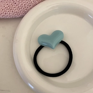 Élastique à cheveux minimaliste avec cœur en résine bleu clair sur une assiette blanche