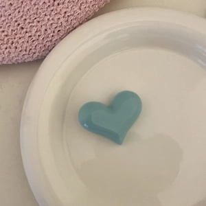 Gros plan d'une pince à cheveux bleue en forme de cœur crème sur une assiette en céramique