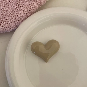 Vue macro d'une pince à cheveux cœur crème sur une assiette en céramique avec décoration