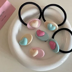 Ensemble pince à cheveux et chouchou en résine cœur macaron sur une assiette blanche