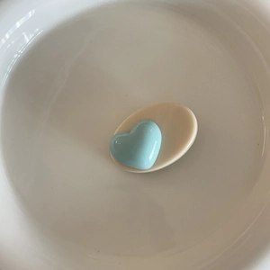 Détail d'un accessoire en résine cœur bleu clair sur base ovale beige au fini brillant