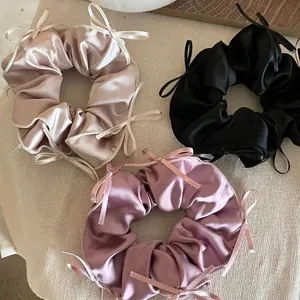 Elegant satin bow scrunchies in champagne, black, and light purple on a textured background