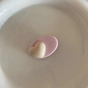 Détail de la pince à cheveux cœur crème au fini brillant dans un bol en céramique
