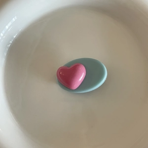 Détail de barrette en résine avec cœur rose et ovale bleu sur un plateau en céramique