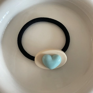Élastique à cheveux cœur crème avec bande noire et cœur 3D bleu sur base ovale blanche