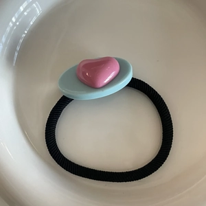 Détail d'élastique à cheveux avec résine ovale bleu clair et cœur rose en relief
