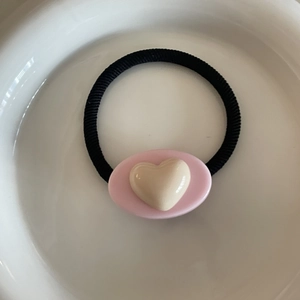 Élastique à cheveux avec un cœur rose et crème sur une assiette blanche épurée