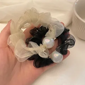 Elegant chiffon scrunchies with iridescent pearls in beige and black, handheld display
