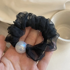 Elegant black chiffon hair scrunchie with a large iridescent pearl on beige background