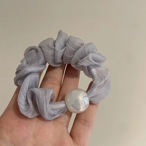 Close-up of pleated organza scrunchie in light purple with a large white decorative pearl